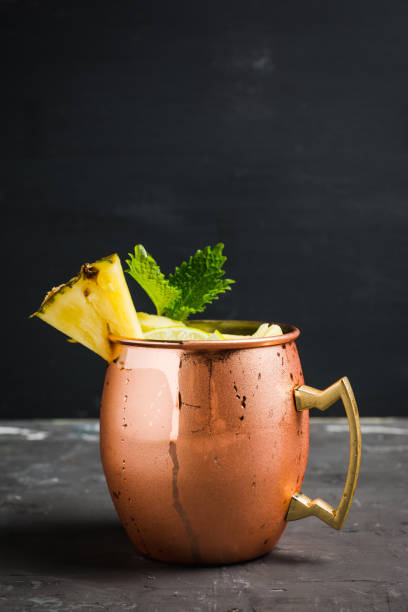 istock Cold pineapple Moscow Mule cocktail in copper mug on the rustic background 910418668