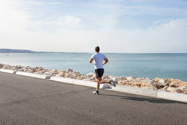 istock Back View of Man Running along Seaside 910421750