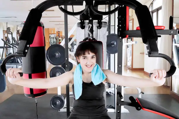 Pretty girl wearing sportswear while exercising with a weight machine in the fitness center