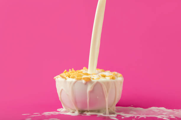 istock pouring fresh healthy milk into bowl with corn flakes on pink 910423284