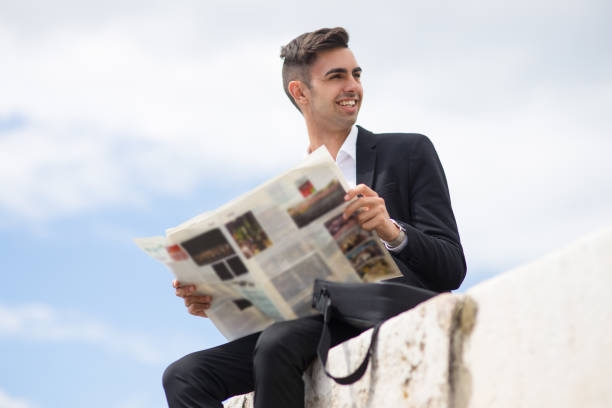 istock Cheerful handsome businessman analyzing newspaper 910423574