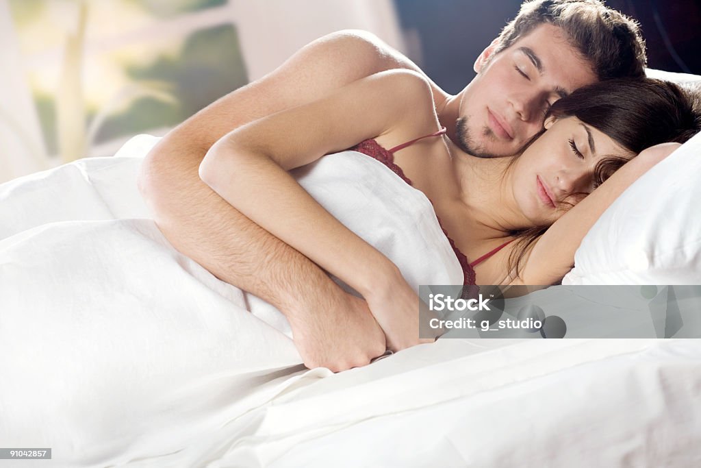 Para spanie i objąć na łóżko w sypialni - Zbiór zdjęć royalty-free (Bielizna damska)