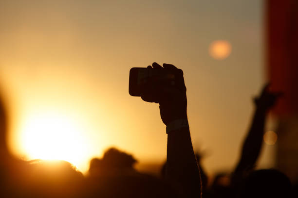 istock Silhouette of smartphone in a hand over crowd. 910429980