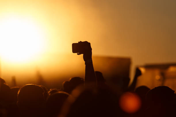 istock Silhouette of smartphone in a hand over crowd. 910430008