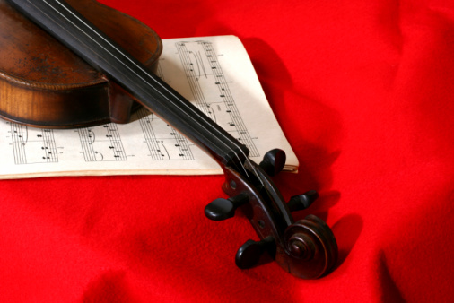 Old violin with music on red background.