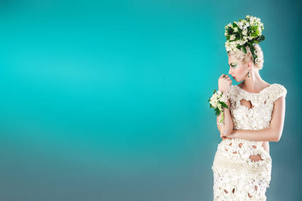 Portrait of a blond pretty girl with bright green white mua, flower bouquet composition on her had, ear-ring, profile, side view. Free place on photo can be used for text inscription, congratulations