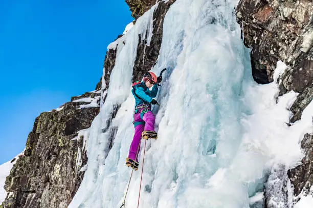 Woman climbing frozen waterfall in the Pyrenees France