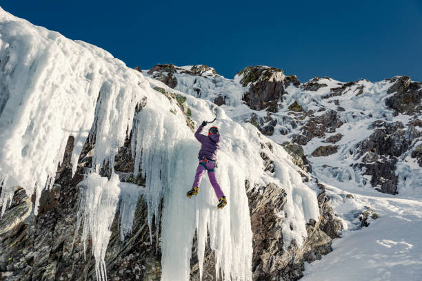 istock Woman ice climbing frozen waterfall 910440722
