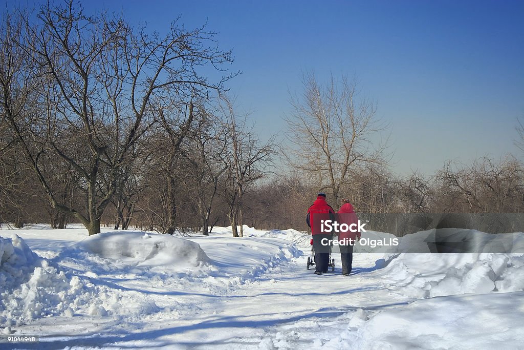 Jeunes parents avec un bébé à marcher dans un parc en hiver - Photo de A l'abandon libre de droits