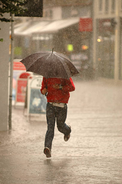 istock A man with an umbrella running through the rain 91045806