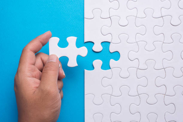 istock Hand holding piece of white puzzle on blue background. 910465624