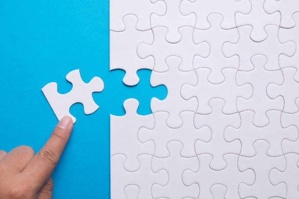 istock Hand holding piece of white puzzle on blue background. 910465632