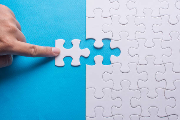 istock Hand holding piece of white puzzle on blue background. 910465638