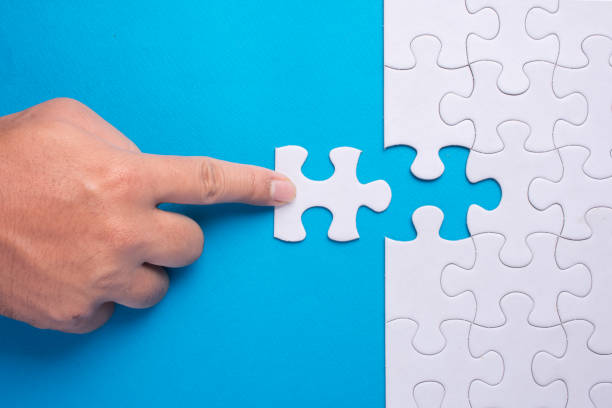 istock Hand holding piece of white puzzle on blue background. 910465642