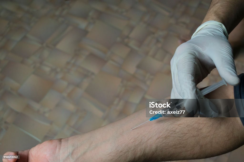 injection of a medical syringe into his hand, a medical glove injecting yourself with a syringe into a vein on the arm Adult Stock Photo