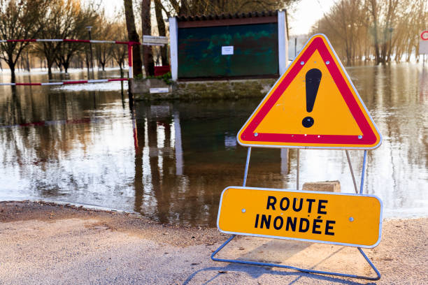 Closeup on warning sign of danger in front of a flooded road ("Route inondee in French") stock photo