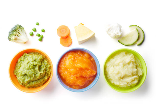 Three bowls of baby puree isolated on white from above Green, yellow and orange baby puree in bowl isolated on white background, top view baby food stock pictures, royalty-free photos & images