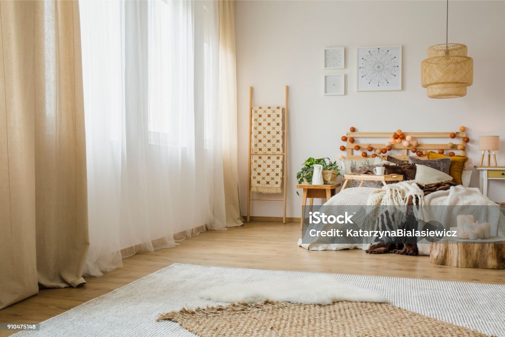 Hygge style bedroom interior Candles on wood next to bed with knit blanket in hygge style bedroom interior with brown curtain and posters Curtain Stock Photo