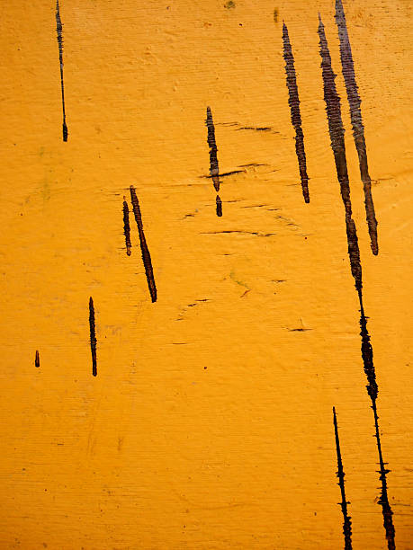 Yellow painted wooden board with black paint splashes stock photo