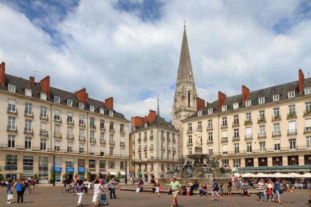 People visiting town square Place Royale in the shopping center of Nantes, France, on a summer day with the Basilique Saint-Nicolas de Nantes in the background, on July 29, 2014