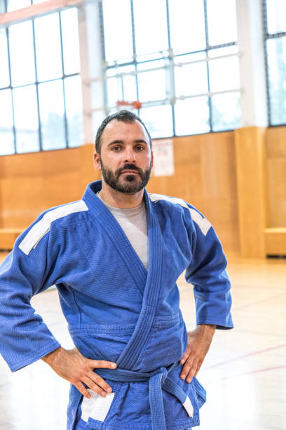 istock Bearded Judoist in Blue Kimono Holding Arms on Hips 910485116