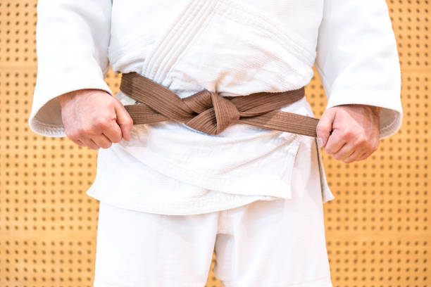 istock Unrecognizable Judoist Tying Brown Belt 910485134