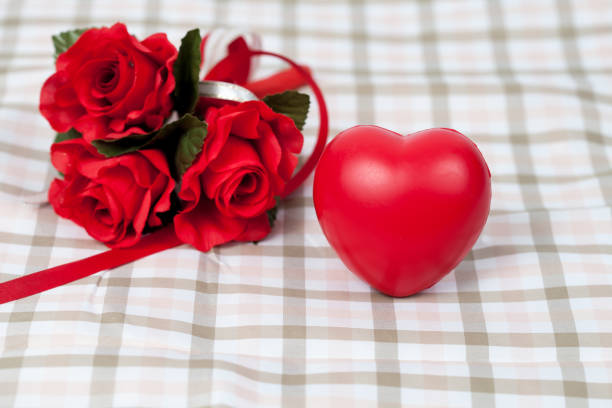 istock Red rose flower and red heart sign on table cloth 910488014