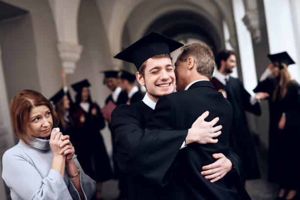 os pais felicitar o estudante, que terminar seus estudos na universidade. - mortar board child female people - fotografias e filmes do acervo