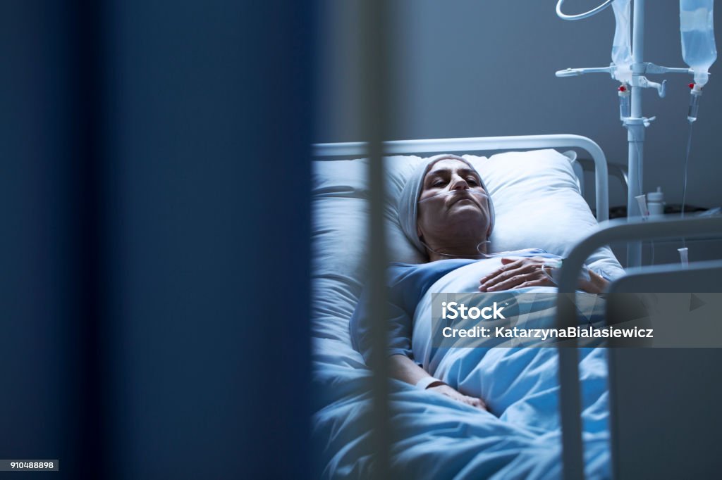 Young woman suffering from cancer Lonely young woman suffering from cancer while lying in hospital bed Patient Stock Photo