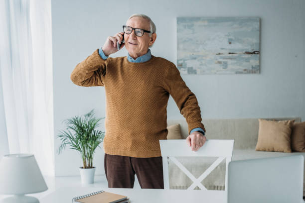 istock Elder smiling man working in office and making phone call 910491782