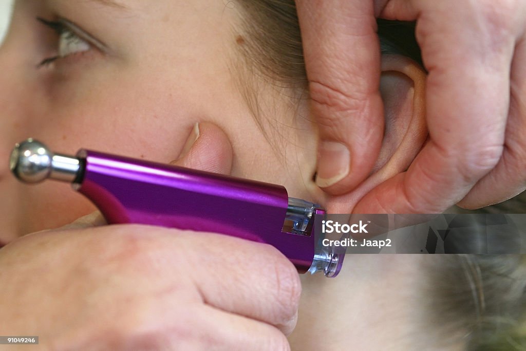 Young girl's headshot, having first earrings shot with purple pistol  Earring Stock Photo