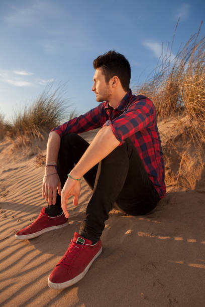 istock Confident young latino man in sitting in the sandy beach 910494586