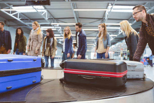 podróżni samolotem czekający na bagaż w pobliżu przenośnika taśmowego - luggage ramp zdjęcia i obrazy z banku zdjęć