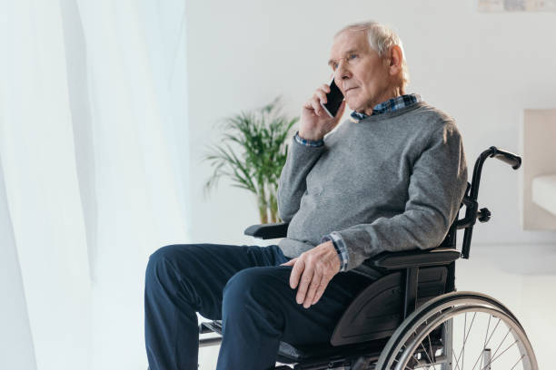 istock Senior man in wheelchair making a phone call in empty room 910499184