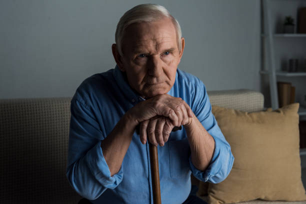 istock Tired senior man leans on a cane while sitting on sofa 910500276