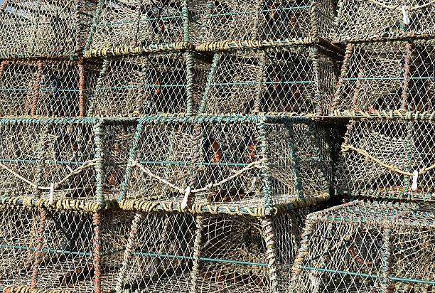 Close-up of large fishing nets and lobster pots seen in an English harbour. The pots are located on a Suffolk beach prior to being loaded on a trawler.