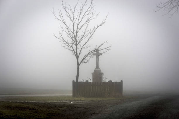 istock cross with jesus next to tree at junction in mist 910505996