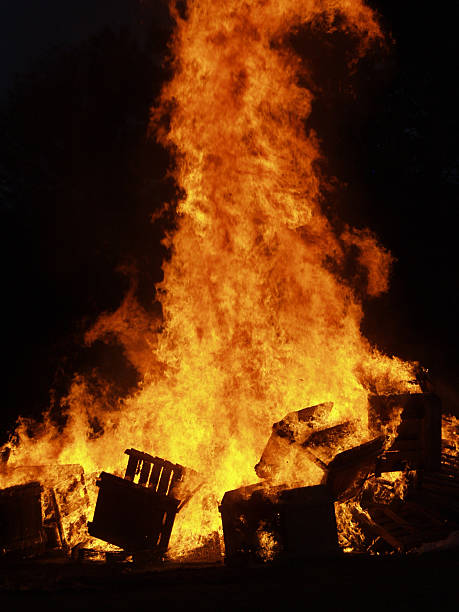 Flames of a bonfire reach high into the night sky 