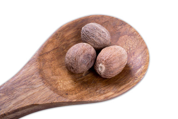 istock whole nutmeg on wooden spoon isolated on white background 910506582