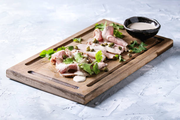 Veal with tuna sauce vitello tonnato Vitello tonnato italian dish. Thin sliced veal with tuna sauce, capers and coriander served on wooden serving board over gray texture background. tonatiuh stock pictures, royalty-free photos & images