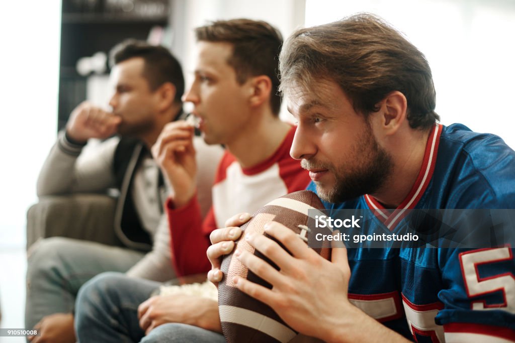 Concentré à regarder le match de football à la maison - Photo de Football américain libre de droits