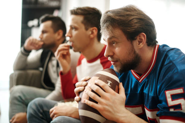 focused watching football game at home - watch imagens e fotografias de stock