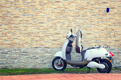 Batumi, Georgia - October, 22, 2017: Electric motor scooter parked near a beautiful wall for charging. Empty copy space for text.