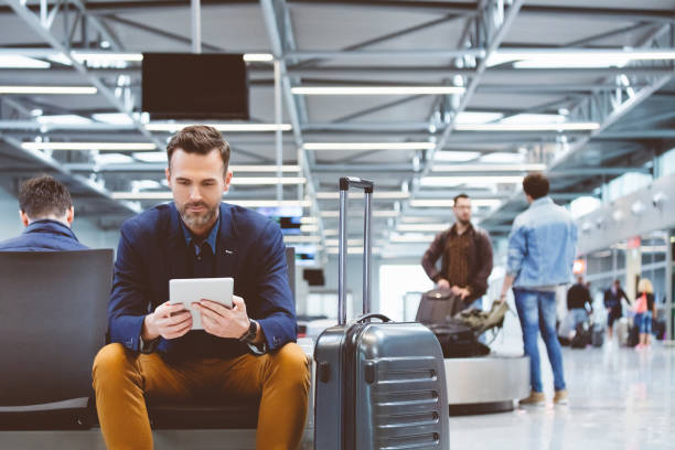 Handsome man waiting in airport lounge, using a digital tablet