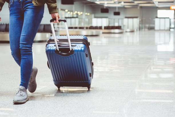 woman walking with suitcase at airport terminal - airplane checkin imagens e fotografias de stock