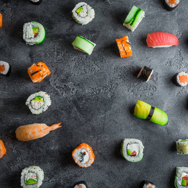 istock Pattern of sushi rolls on a dark background. Japanese food frame. Flat lay. 910520098