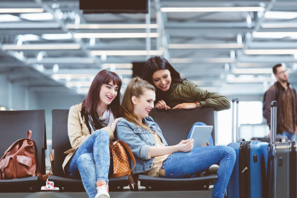 istock Female friends waiting for flight in airport lounge, using a digital tablet 910523576
