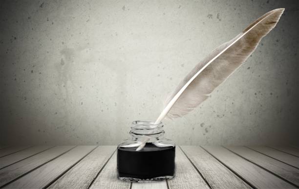istock Feather quill pen and glass inkwell isolated on background 910527576