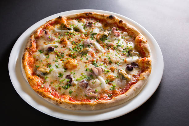 istock pizza with mussels, made on wood, on black background 910531330