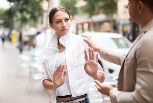 Photo of Unhappy girl getting rid of unwelcome stranger outdoors